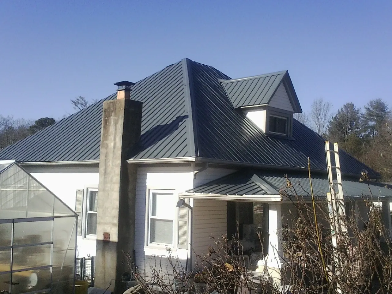 Dark blue standing seam metal roof on a white farmhouse with dormer — Slate & Tile Roof Repair by Roofing Brothers in Sutherland Springs