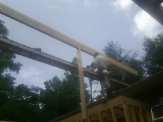 Carpenter setting a ridge beam over a new addition frame — Ice Dam Removal by Roofing Brothers in Sutherland Springs