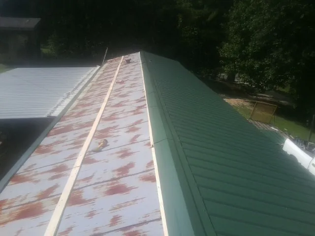Old rusted panels beside newly installed green metal roofing — Wind Damage Roof Repair by Roofing Brothers in Sutherland Springs