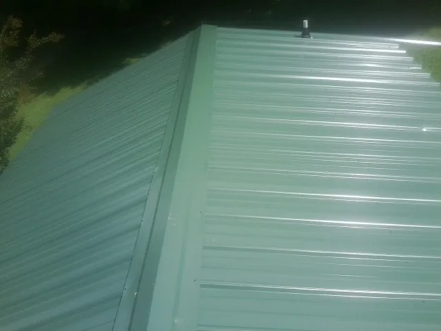 New green metal panels meeting at the ridge of a roof — Flat Roof Repair work by our crew in Sutherland Springs