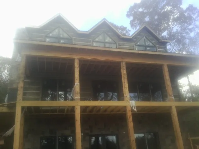 Dormers and porch framing on a large log home under construction — Roof Coating work by our crew in Sutherland Springs