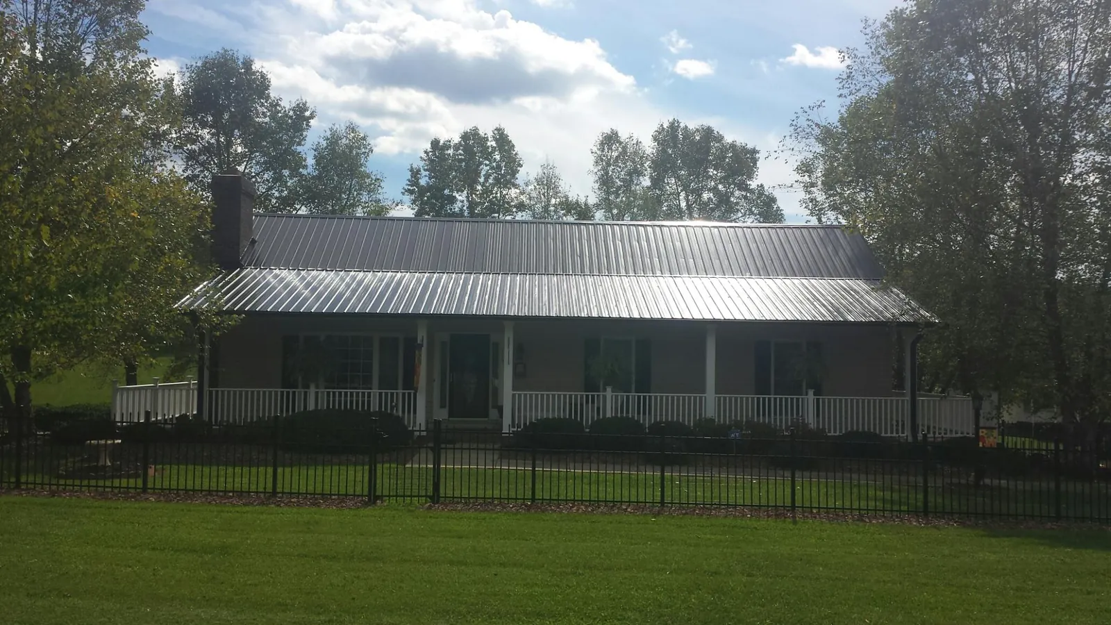 Gray metal roof on a brick ranch with a full width front porch — Gutter Guard Installation work by our crew in Sutherland Springs