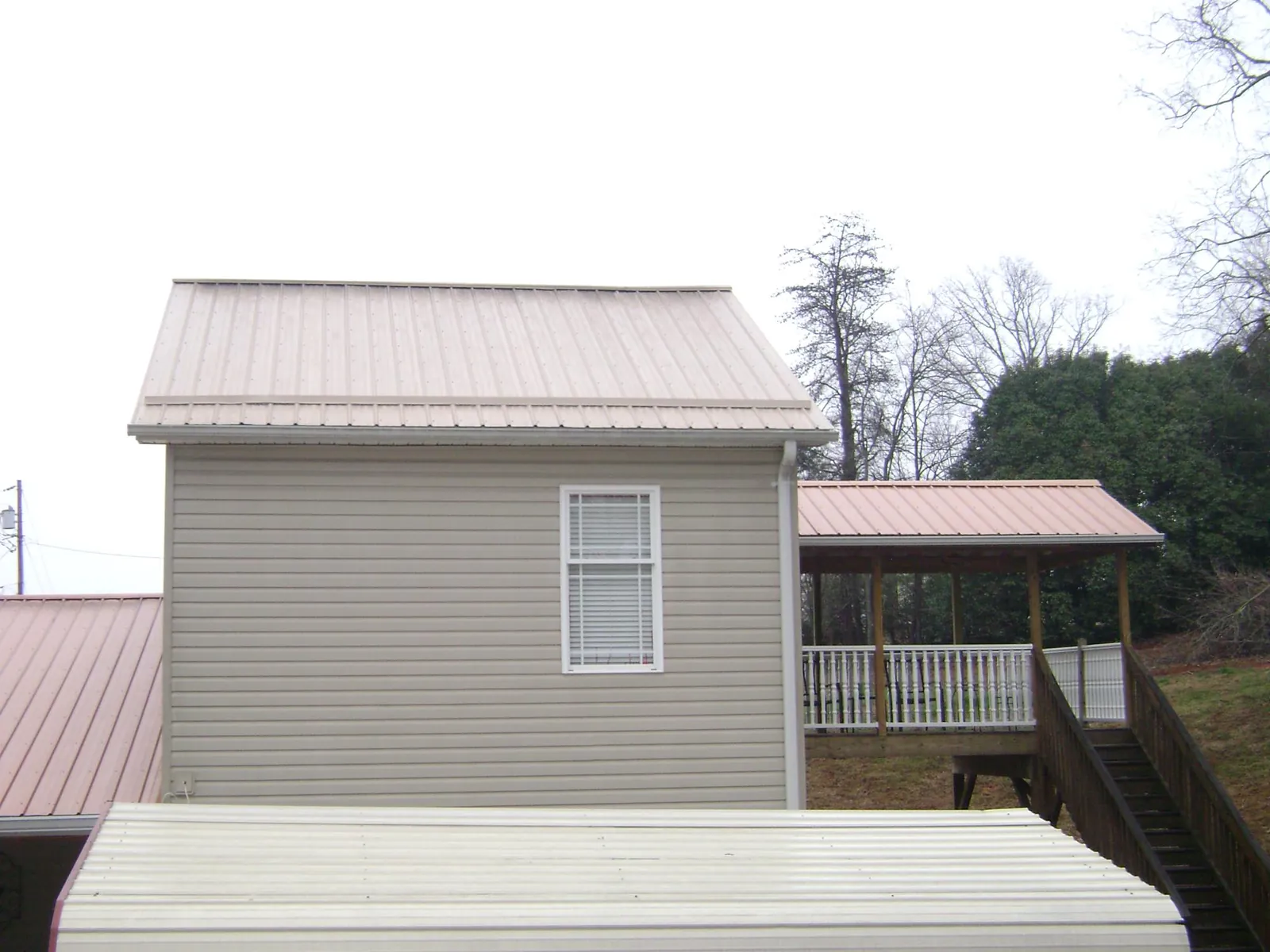 Tan metal roofs on a two story addition and attached porch, from a Roof Replacement job in Sutherland Springs