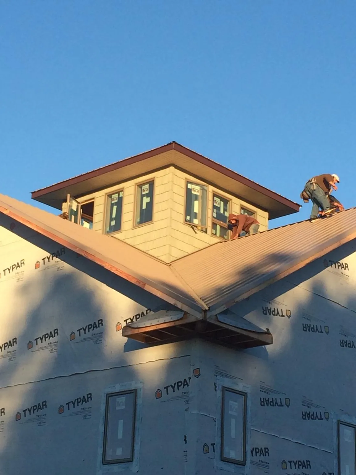Roofers working around a rooftop cupola on a new metal roof at sunset — Roof Waterproofing in Sutherland Springs by Roofing Brothers